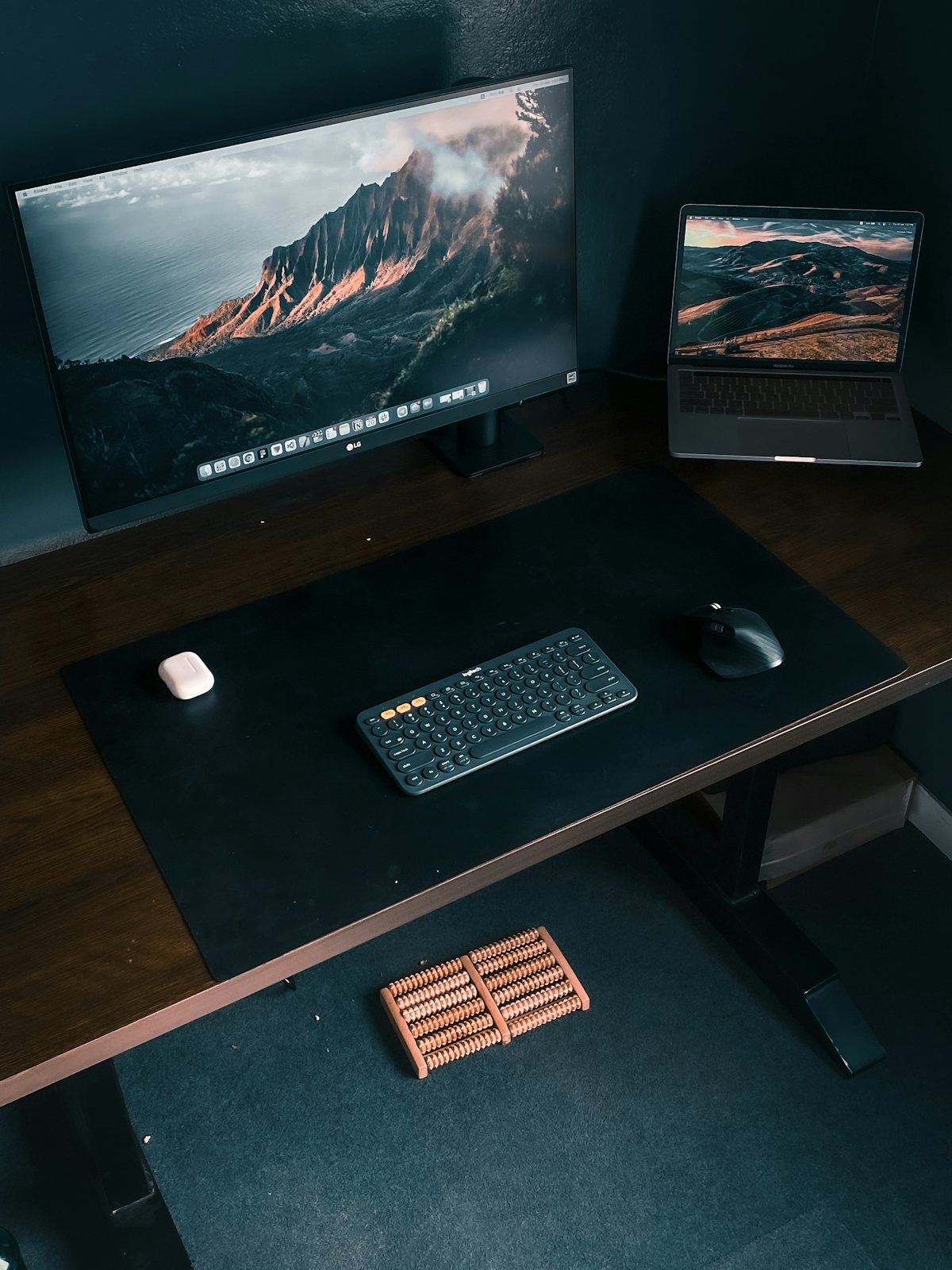 A dark, minimal workspace with a monitor, laptop and keyboard
