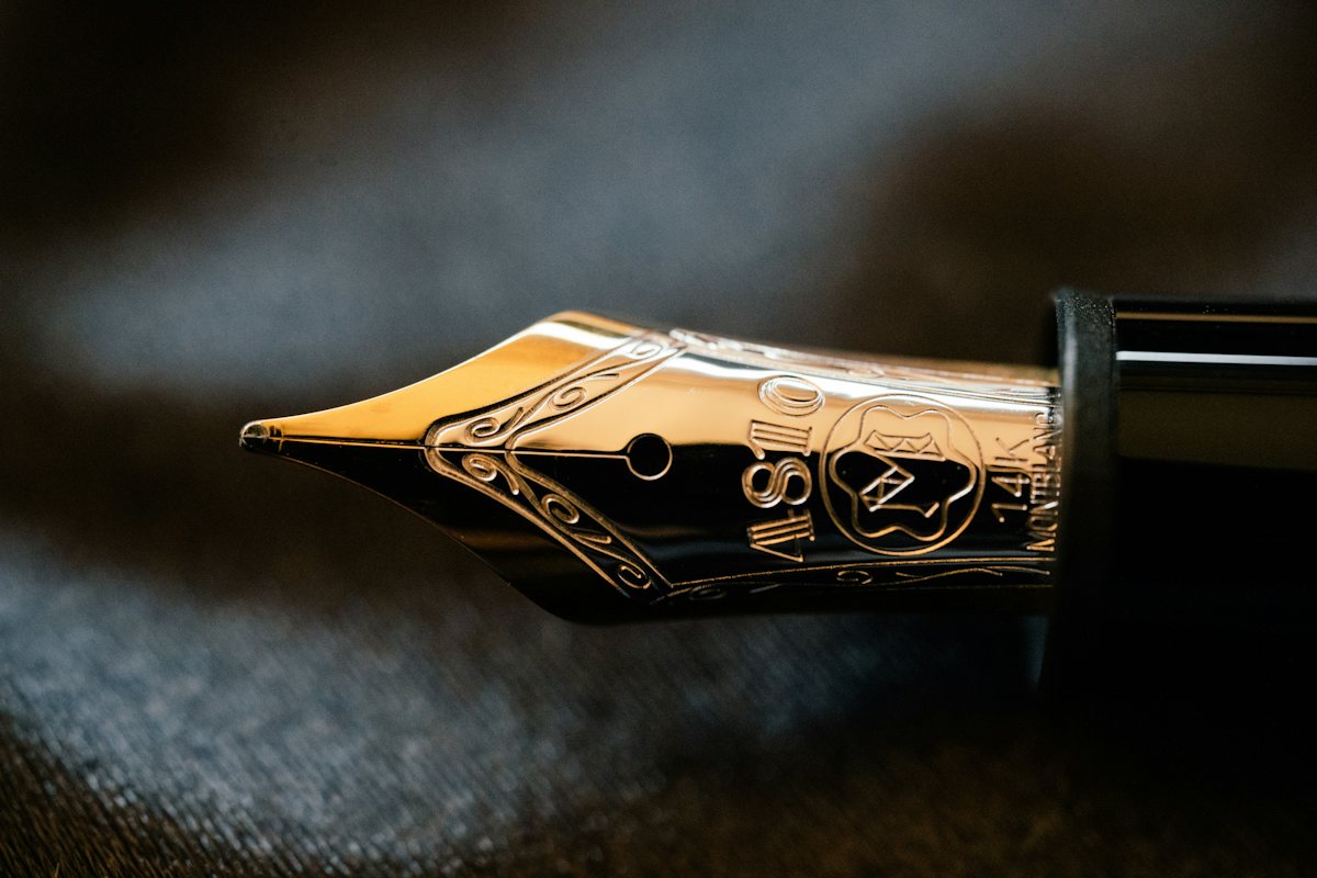 Close-up of a gold fountain pen nib on dark fabric